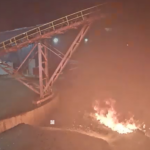 dark image of a fire on the ground outside of a facility