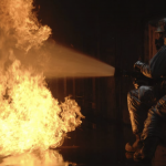 image of a fire hose blasting water, at full force, directly on a fire