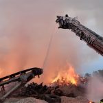 Cranes are putting out a fire in an industrial yard