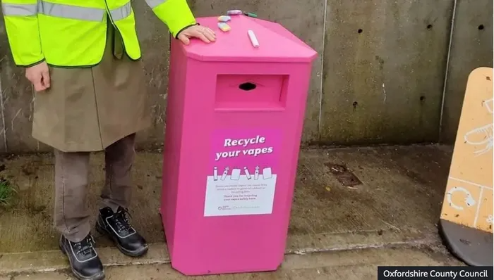 A pink container on a sidewalk designated for recycling vapes. 